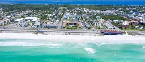 Vue aérienne d’une ville côtière avec une plage, des immeubles résidentiels et un port de plaisance.