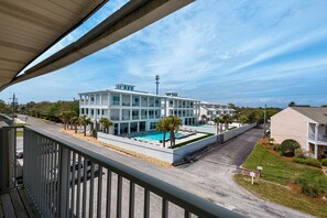 Un hotel moderno de varios pisos con piscina, balcones y césped bien cuidado.