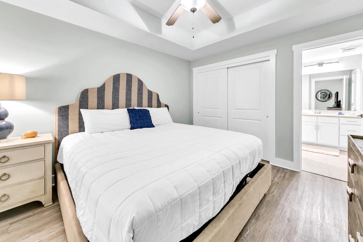 A bedroom with a bed, a nightstand, a dresser, and a ceiling fan.