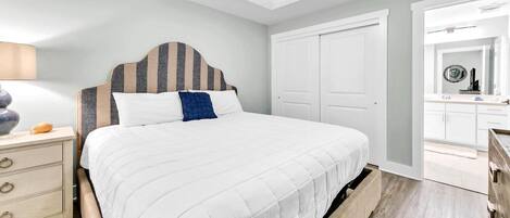A bedroom with a bed, a nightstand, a dresser, and a ceiling fan.
