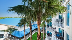 Et hotel med flere etager, altaner, en pool og palmer.