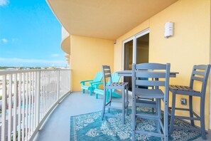 A balcony with a table and chairs, a patterned rug, and a view of the ocean. - Calypso 3-406 - Paradise by the Pier (Panama City Beach)
