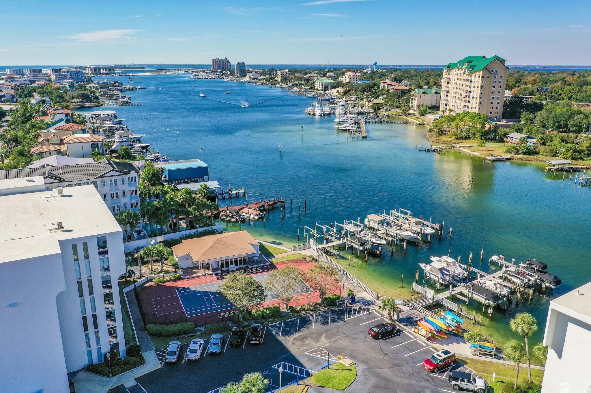 A marina with boats docked, a parking area, and buildings with a view of the water.