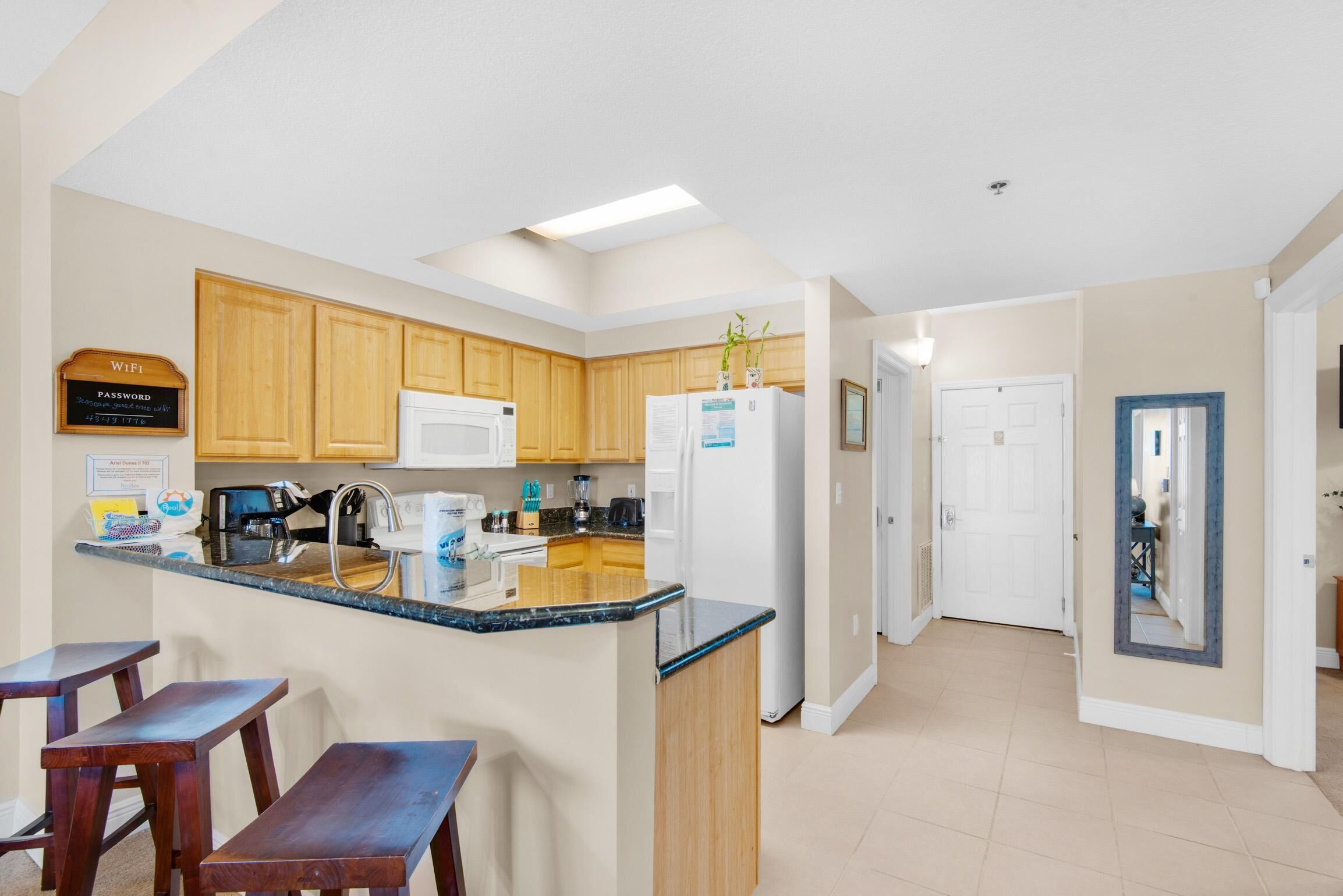 A modern kitchen with wooden cabinets, a white refrigerator, and a built-in island with bar stools.