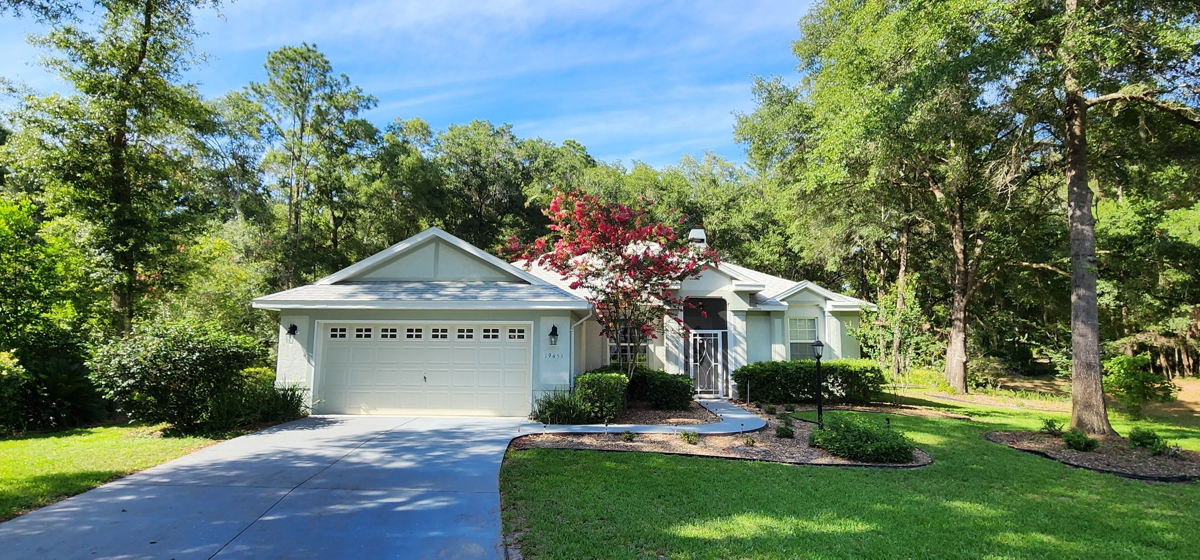 A two-story house with a garage, surrounded by trees and a well-maintained lawn.