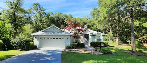 A two-story house with a garage, surrounded by trees and a well-maintained lawn.