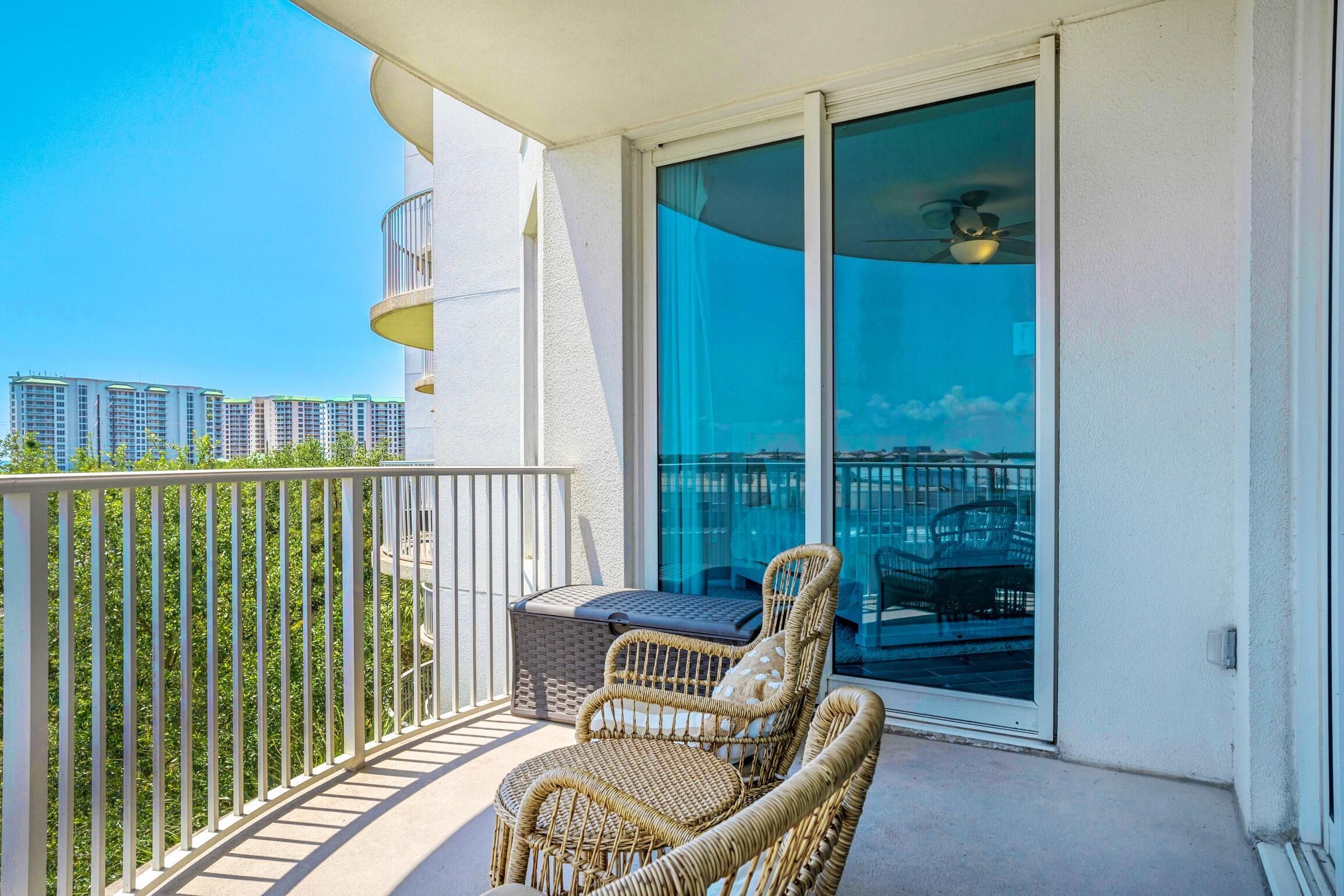 A balcony with wicker chairs, a small table, and a sliding glass door.