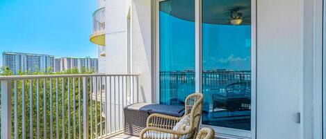 A balcony with wicker chairs, a small table, and a sliding glass door.