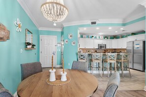 A dining area with a round table, chairs, and a chandelier.