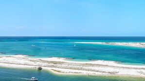 A coastal landscape with clear turquoise waters, sandy beaches, and a boat in the foreground. - Emerald Grande W1221 (Destin)