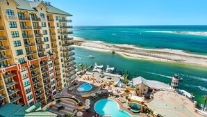 A resort with multiple swimming pools, a beachfront, and a high-rise building with balconies. - Emerald Grande W1221 (Destin)