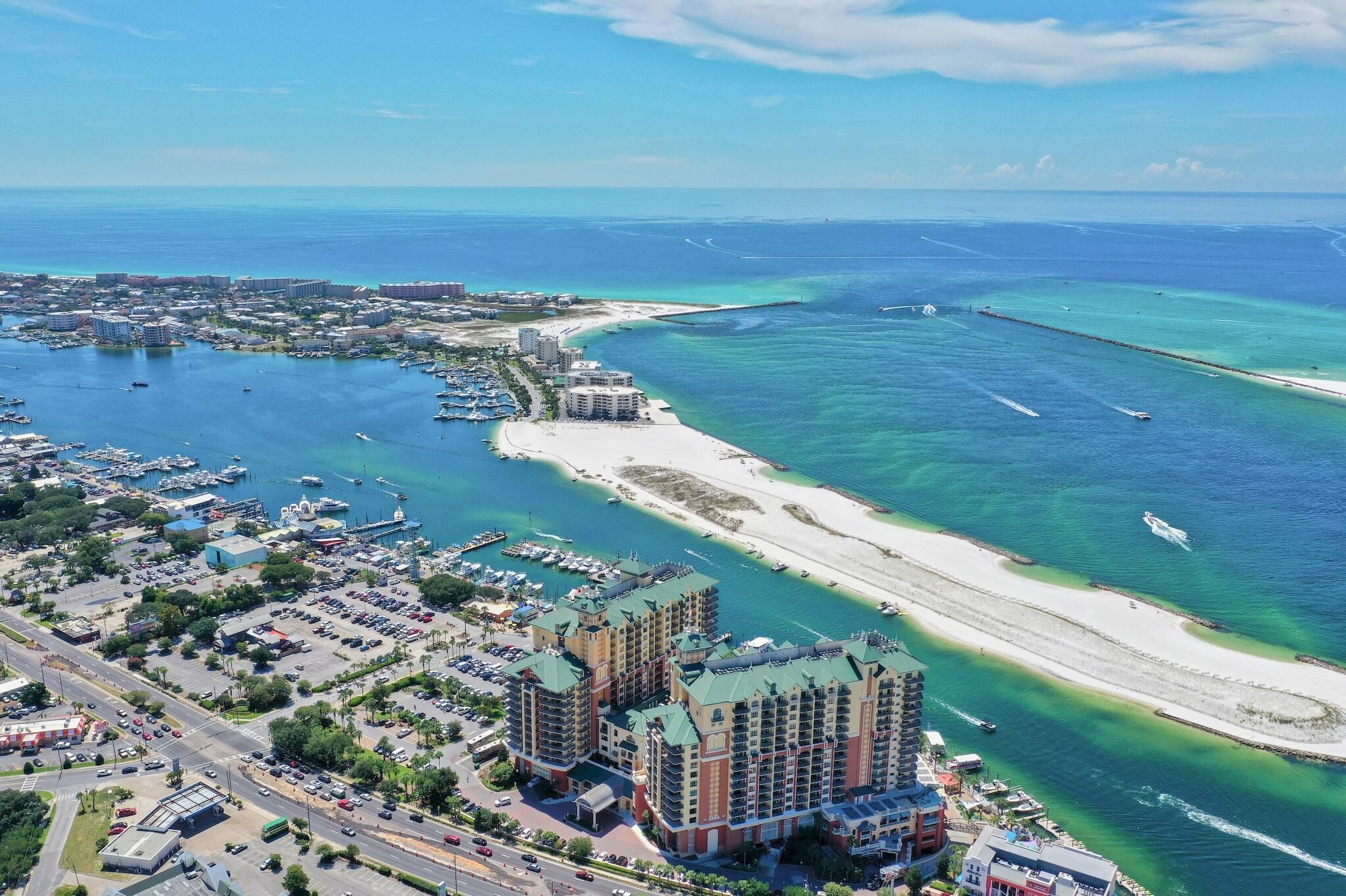 Vista aérea de una ciudad costera con un puerto deportivo, una playa y un complejo hotelero.