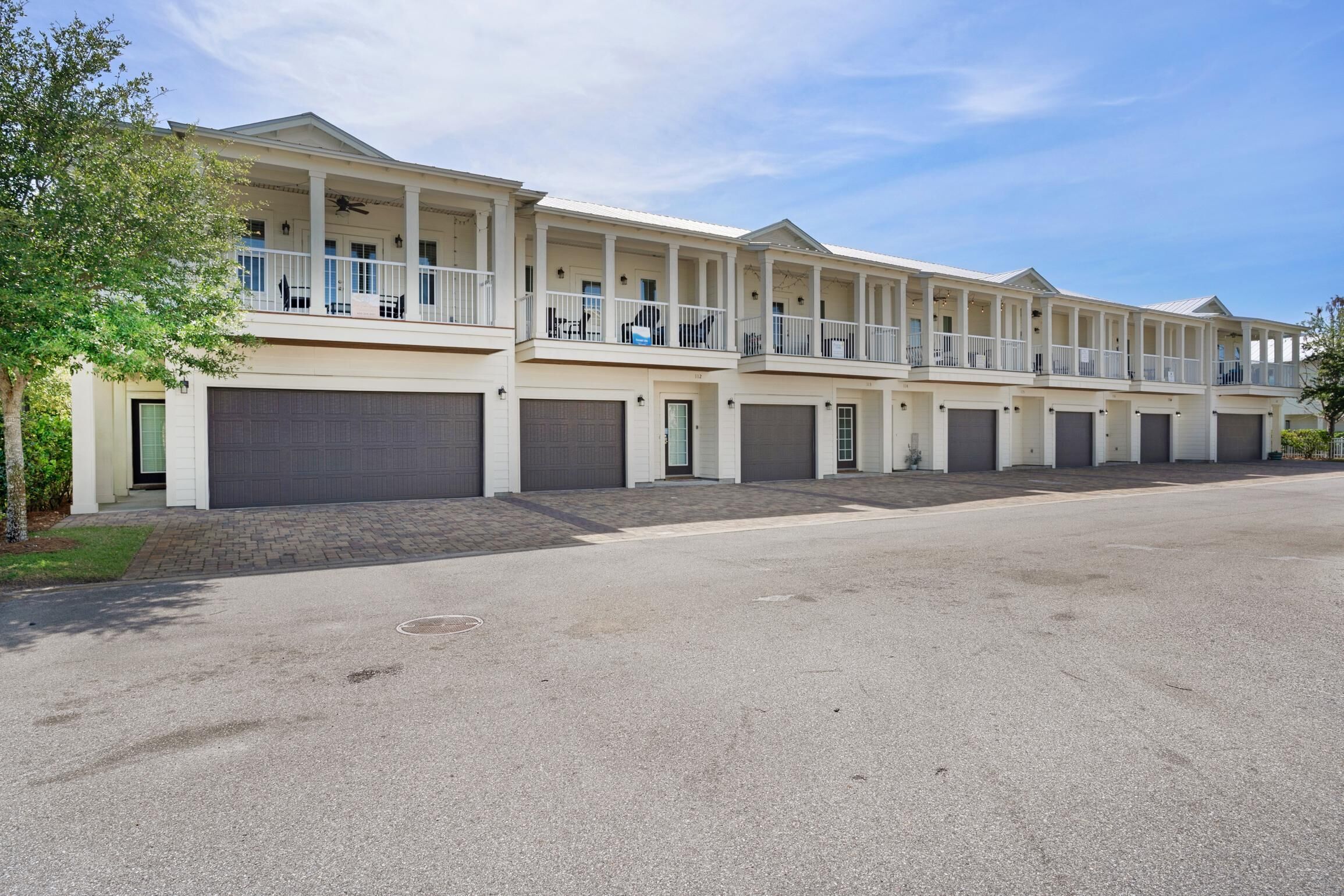 A row of two-story townhouses with balconies, garage doors, and a paved driveway.