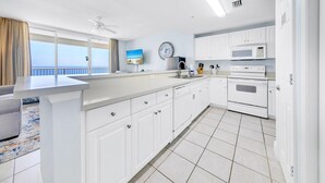 A modern kitchen with white cabinets, a microwave, an oven, and a sink.