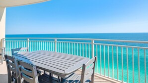 Un balcon avec une table et des chaises donnant sur une mer turquoise.