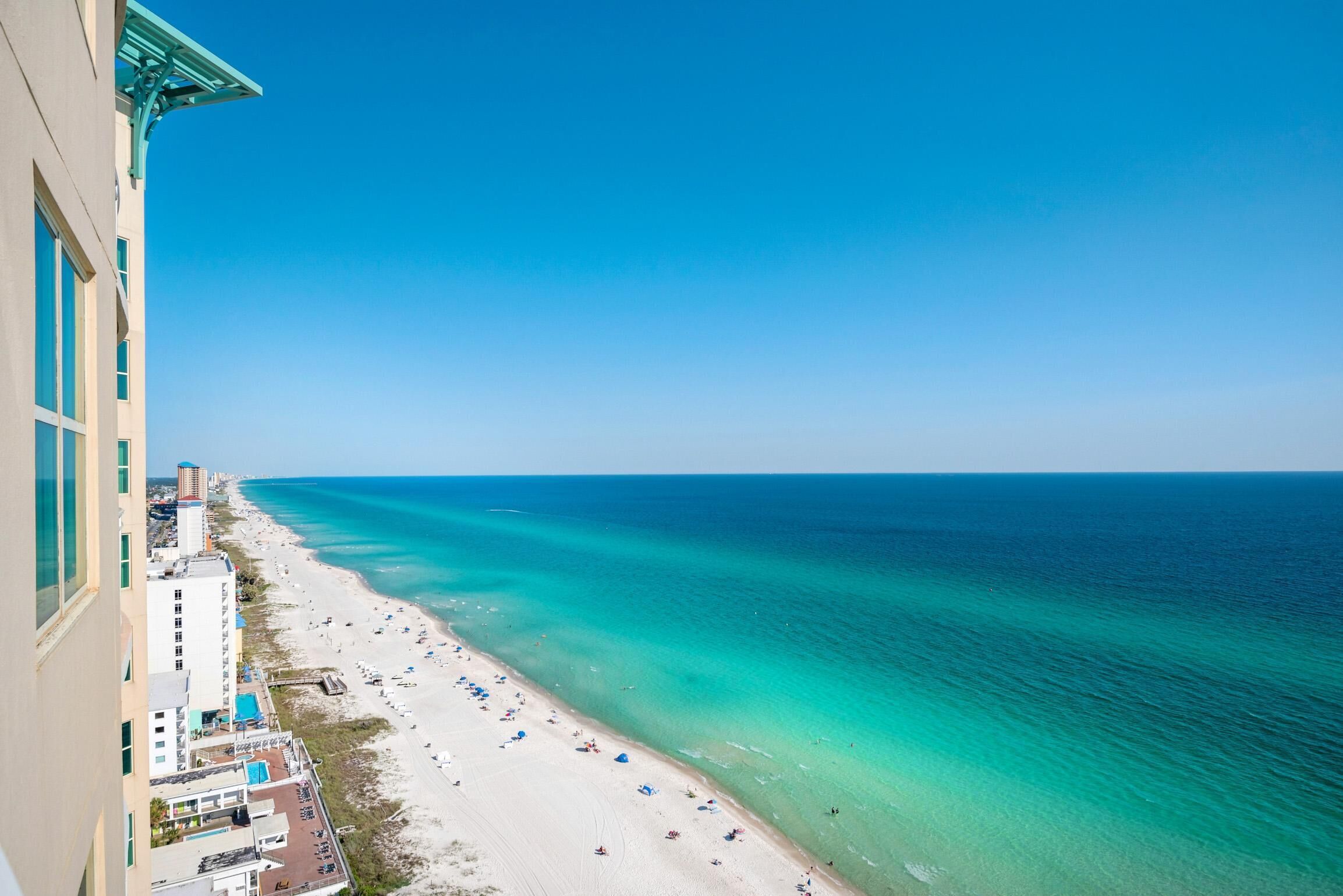 A beach view from a high-rise building with a clear sky.