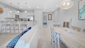 Una cucina moderna con mobili bianchi, elettrodomestici in acciaio inossidabile e lampade a sospensione.