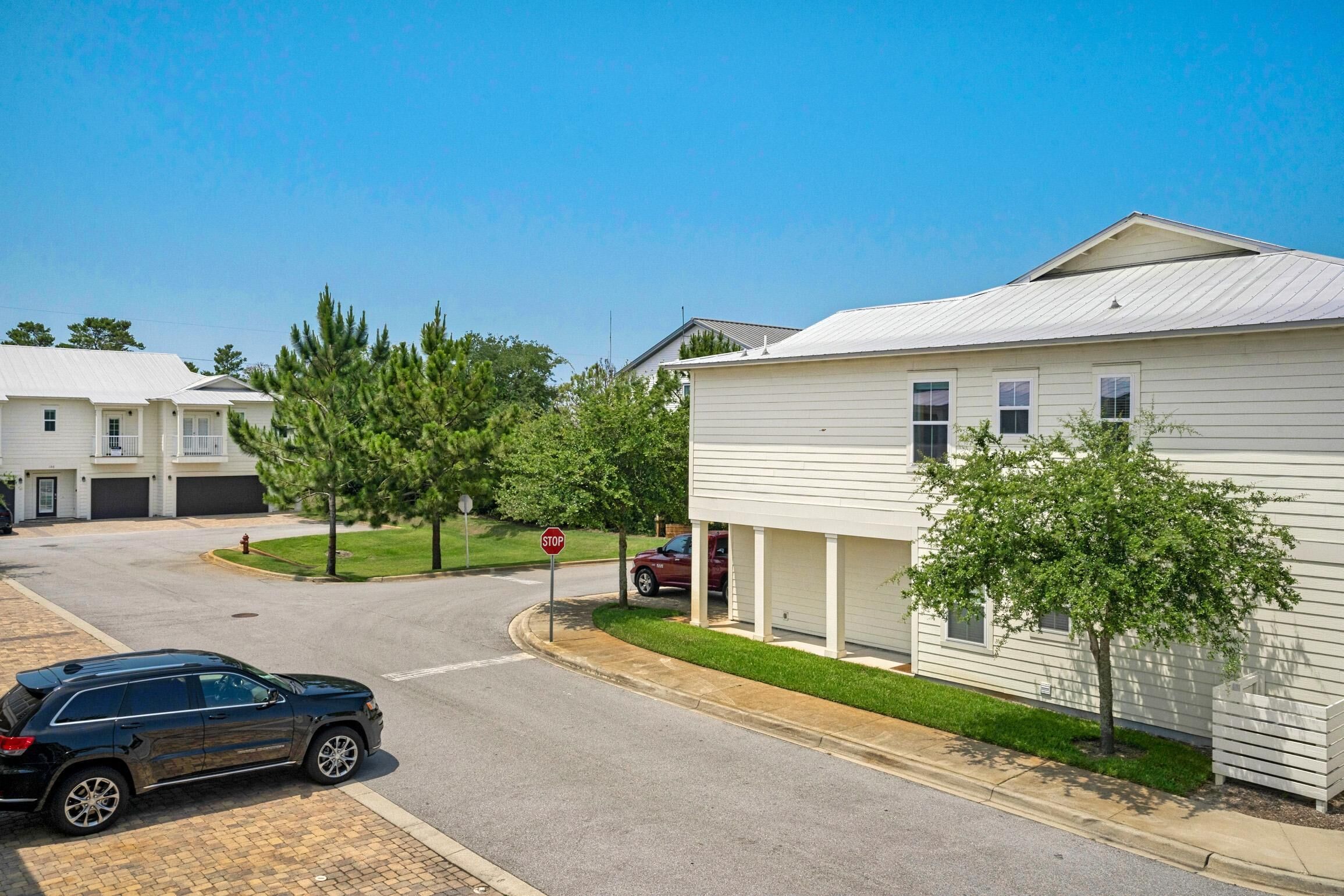A residential street with houses, a stop sign, and a parked SUV.