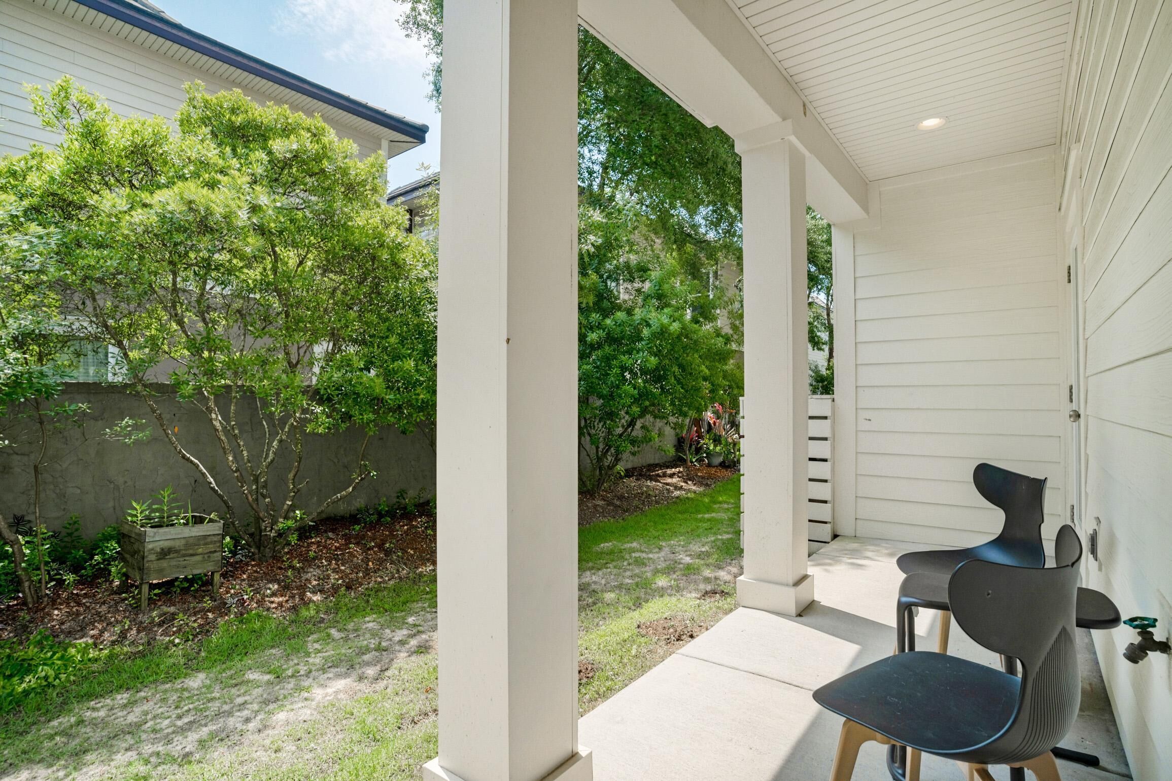A covered patio with a concrete floor, two chairs, and a small table.