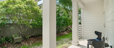 A covered patio with a concrete floor, two chairs, and a small table.