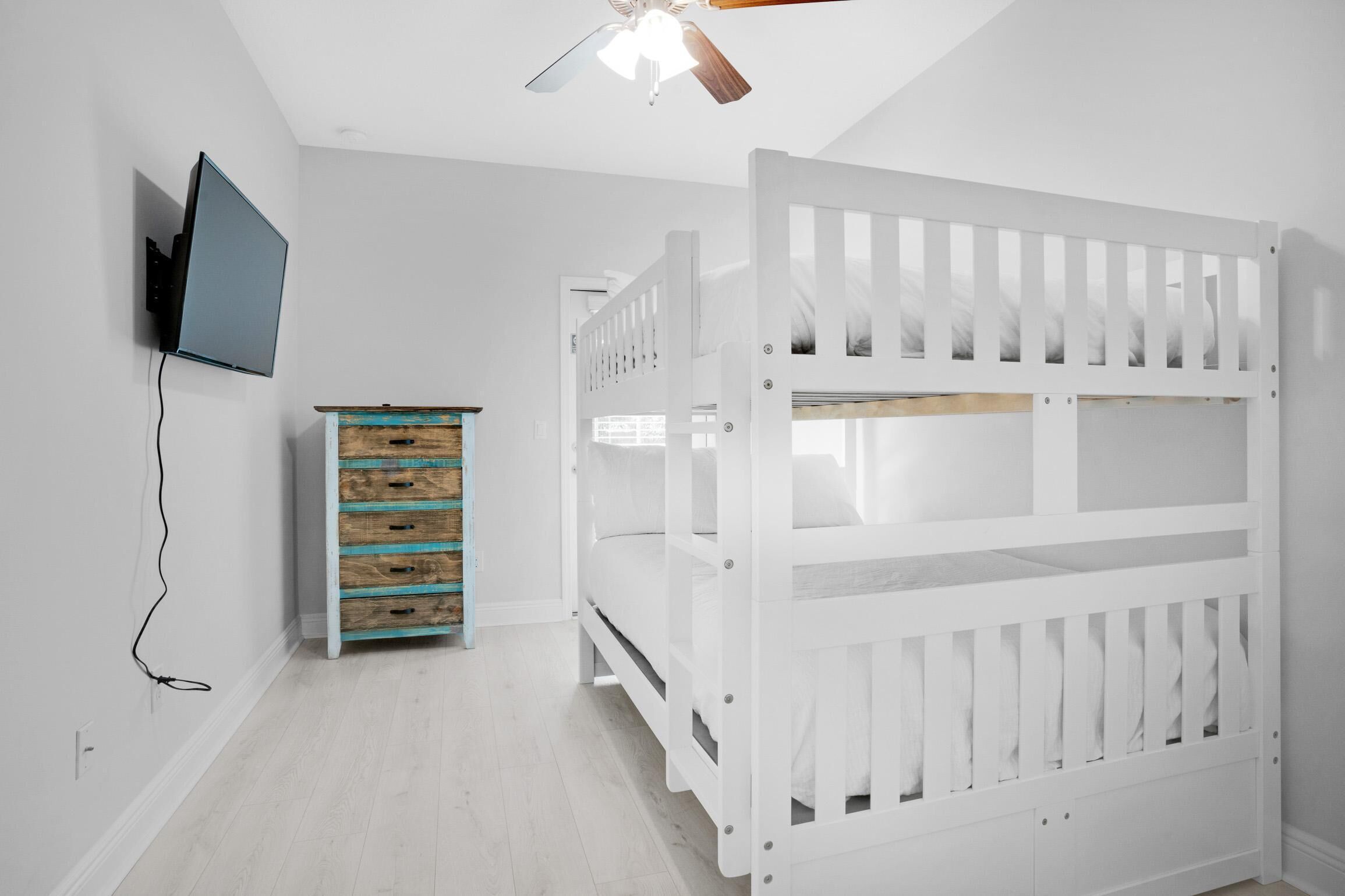 Ein Kinderzimmer mit einem Etagenbett, einer Kommode und einem an der Wand befestigten Fernseher.