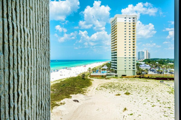 A beach view with a tall hotel building, sandy beach, and ocean.