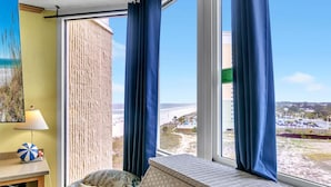 A room with a large window, a view of the beach, a lamp, and a beach ball on a table. - Top of the Gulf 822 (Panama City Beach)