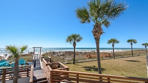 A wooden deck leading to beach chairs and a palm tree, overlooking the ocean. - Top of the Gulf 822 (Panama City Beach)