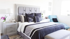 A modern bedroom with a large bed, bedside tables, a nightstand, and a chair. - New Villa Deluxe, Golf Club, Punta Cala 205 (Nuevo Nayarit)