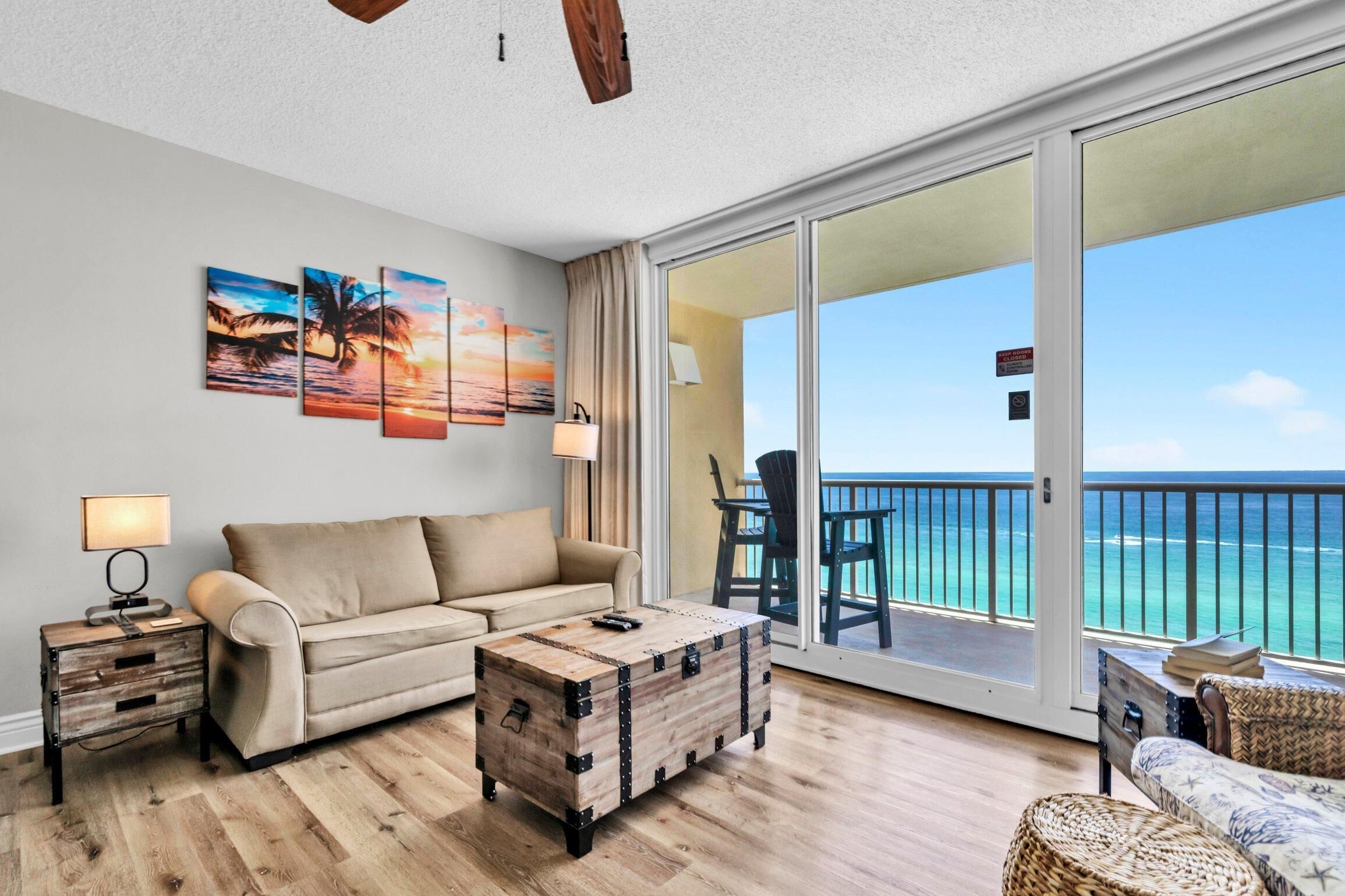 A spacious living room with a sofa, a wooden coffee table, and a view of the ocean through large sliding doors.
