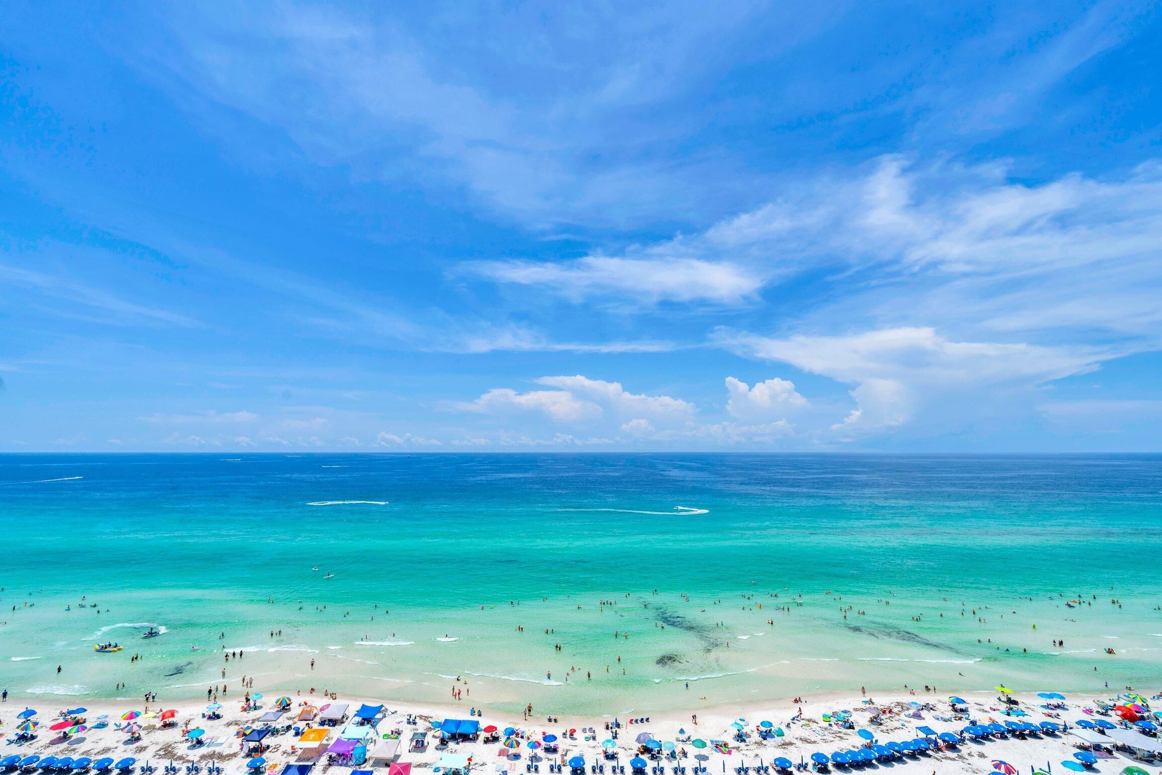 A beach with clear turquoise waters and a sandy shore.