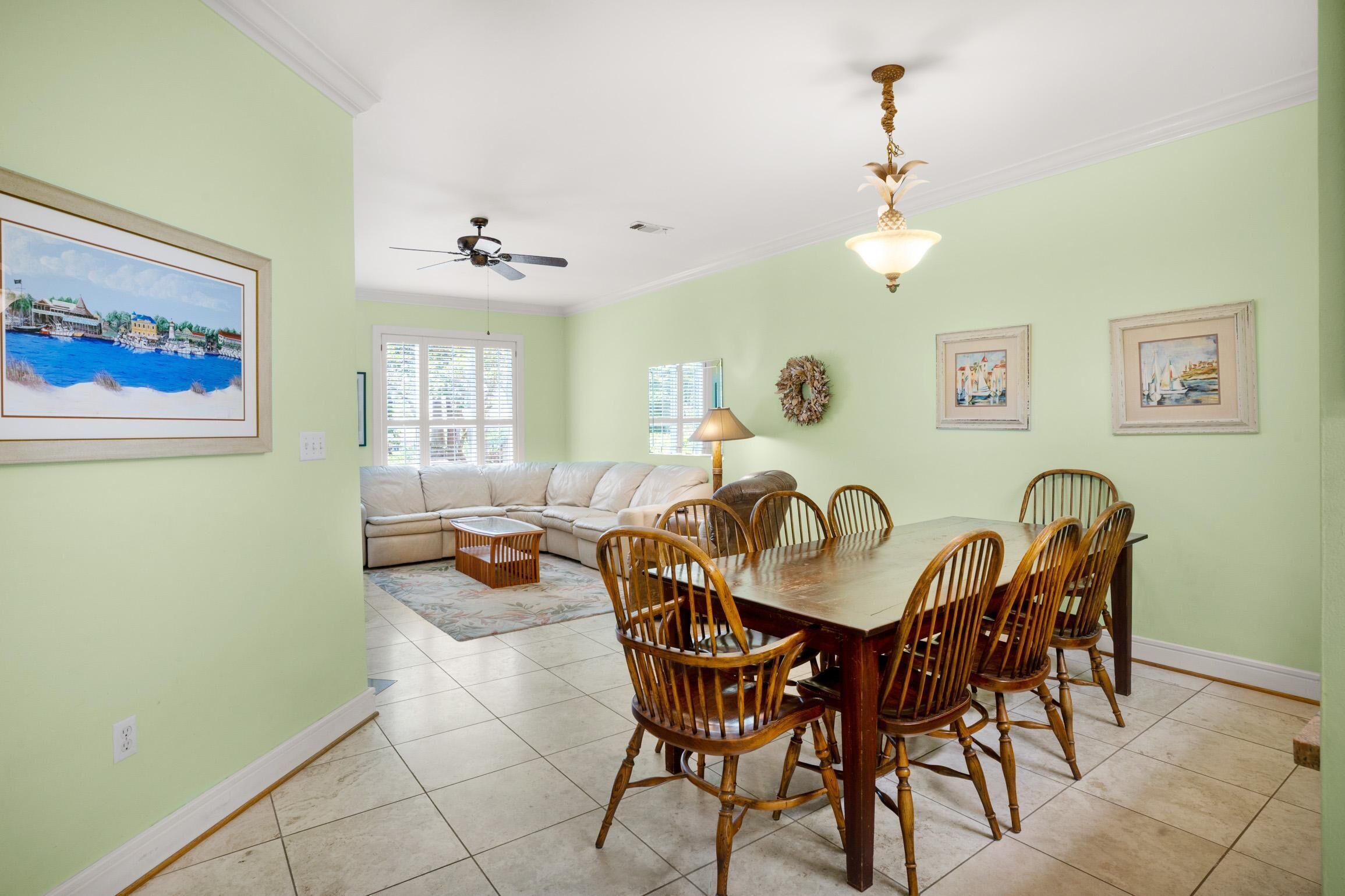 A dining area with a wooden table and chairs, a ceiling fan, and a chandelier.