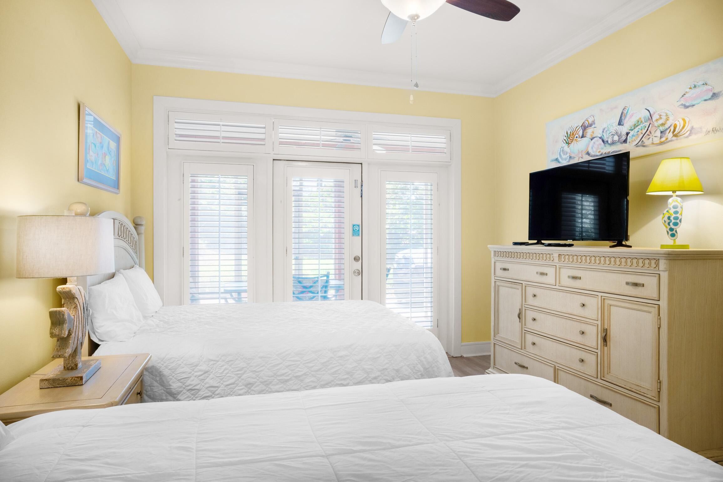 A hotel room with two beds, a TV, a dresser, and a painting on the wall.