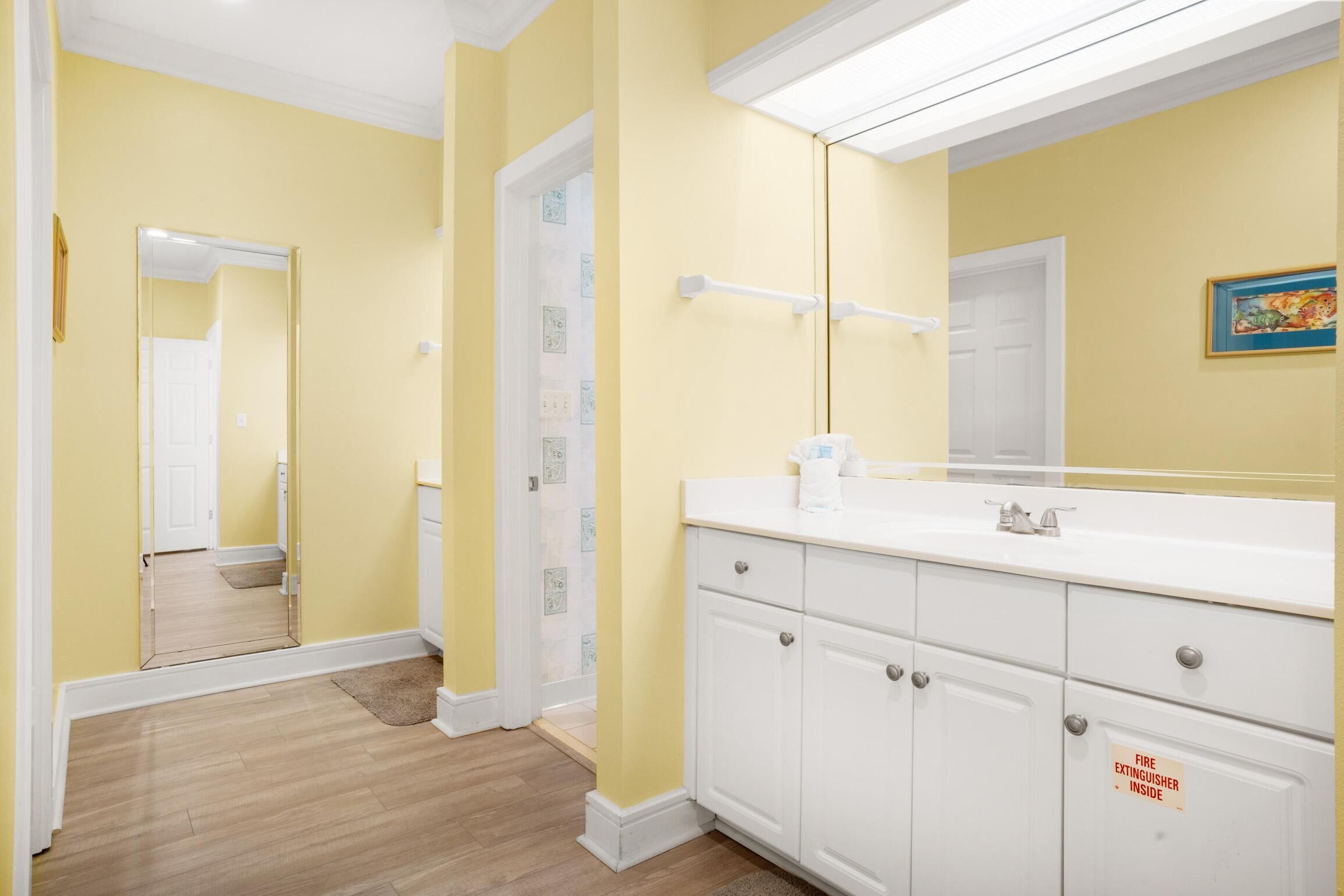 Une salle de bain avec des murs jaunes, un lavabo blanc et un miroir.