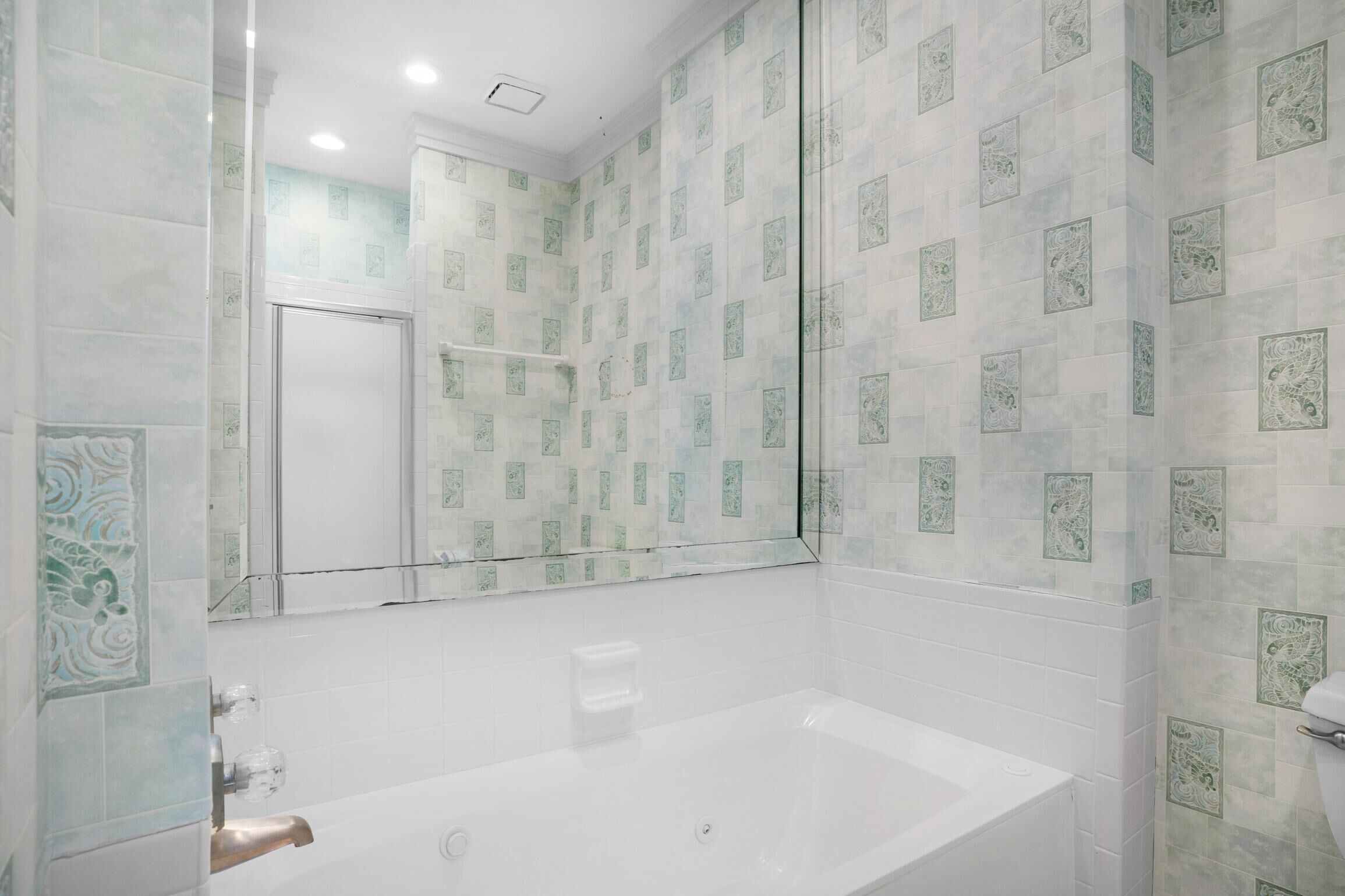 A bathroom with a bathtub, a glass shower enclosure, and patterned tiles.