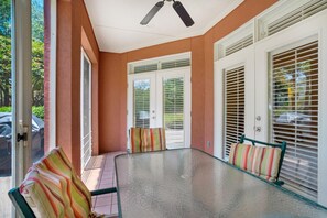 A glass-top table with chairs, a ceiling fan, and a door with a window. - Tivoli Terrace #5431 (Miramar Beach)