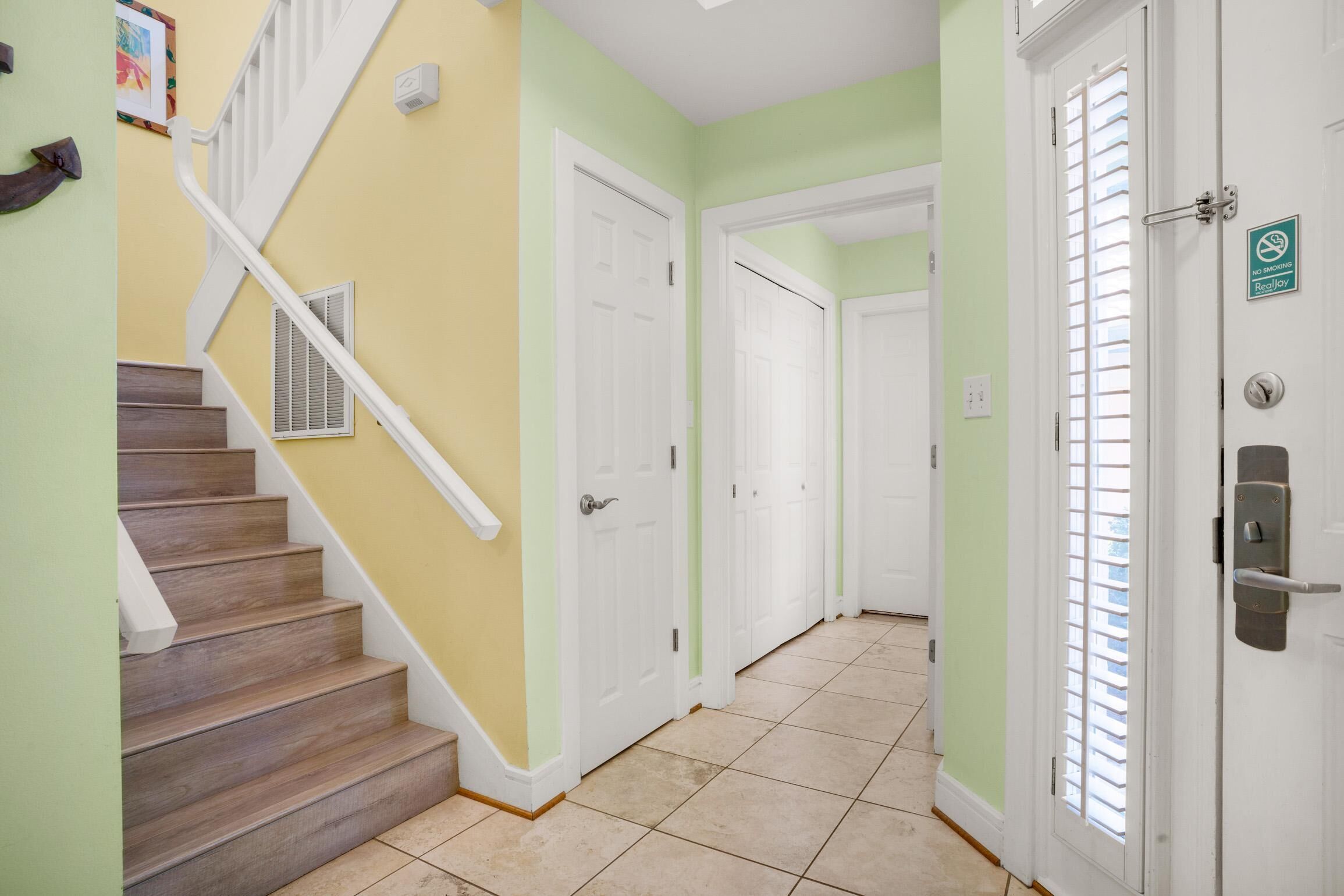 A hallway with a staircase, white doors, and a no smoking sign.