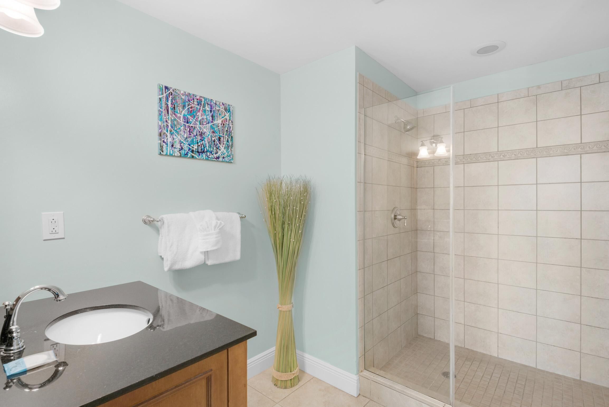 A bathroom with a sink, a shower, and a wall-mounted towel rack.