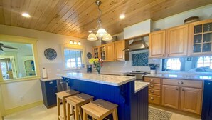 A kitchen with wooden cabinets, a blue island with stools, and a hanging light fixture. - Large Groups! Pine Point Beach 8 BDRM! (Scarborough)