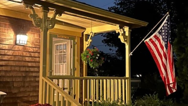 A house with a porch, an American flag, and a full moon in the sky. - Large Groups! Pine Point Beach 8 BDRM! (Scarborough)