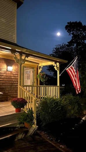 Ein Haus mit Veranda, einer amerikanischen Flagge und einem Vollmond am Himmel.