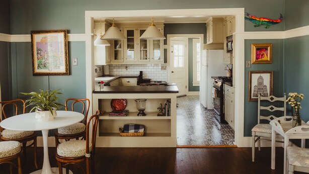 A kitchen with white cabinets, a central island, and pendant lighting. There is a dining area with a table and chairs, and a plant on the table. - Easy walk to UL, Downtown, Girard park, and multiple music venues. Pet friendly! (Lafayette)