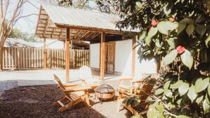 A covered outdoor seating area with wooden chairs and a fire pit. - Easy walk to UL, Downtown, Girard park, and multiple music venues. Pet friendly! (Lafayette)