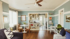 A spacious living room with a dark sofa, a white coffee table, and a dining area with a white table and chairs. - Easy walk to UL, Downtown, Girard park, and multiple music venues. Pet friendly! (Lafayette)