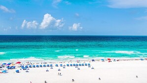 Ein Strand mit weißem Sand, türkisblauem Wasser und blauem Himmel.