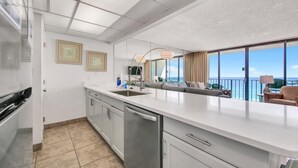 Eine moderne Küche mit einer großen Kochinsel, ein Essbereich mit Aussicht und ein Balkon mit Blick.