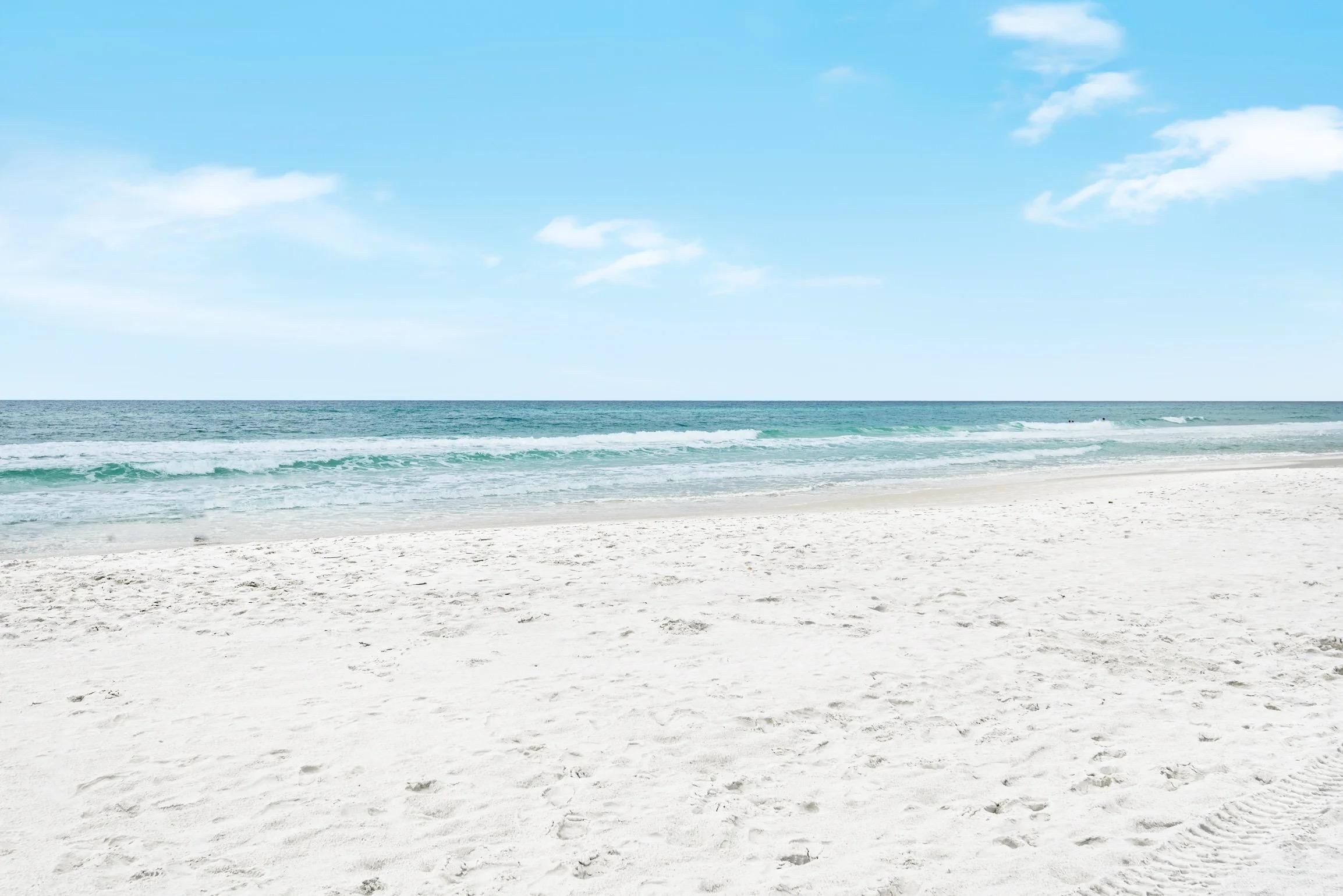 A beach with white sand and a clear blue sky.