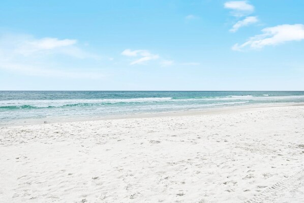 Una playa con arena blanca y cielo azul despejado.