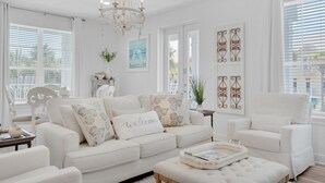 A spacious living room with a white sofa set, a chandelier, and decorative wall art. - Gulf Place Residences 109 (Santa Rosa Beach)