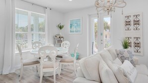 A bright, white interior with a dining area, a sofa, and a chandelier. - Gulf Place Residences 109 (Santa Rosa Beach)